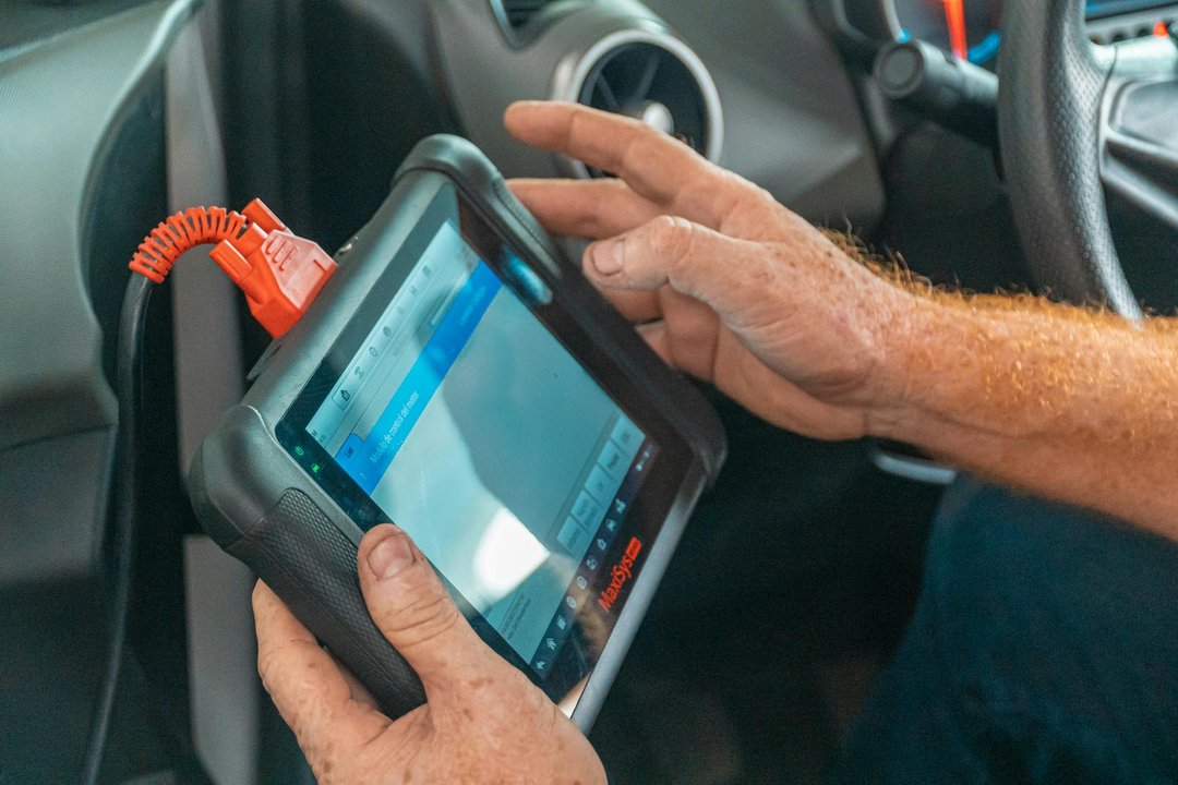 Specialist auto realizând o activare CarPlay prin codare, folosind portul de diagnoză al unui BMW.