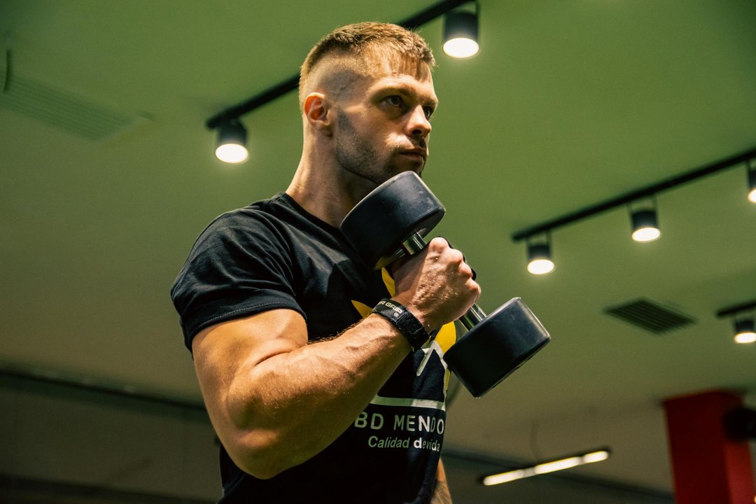 Bărbat la sală verificând datele de antrenament de forță pe un fitness tracker modern