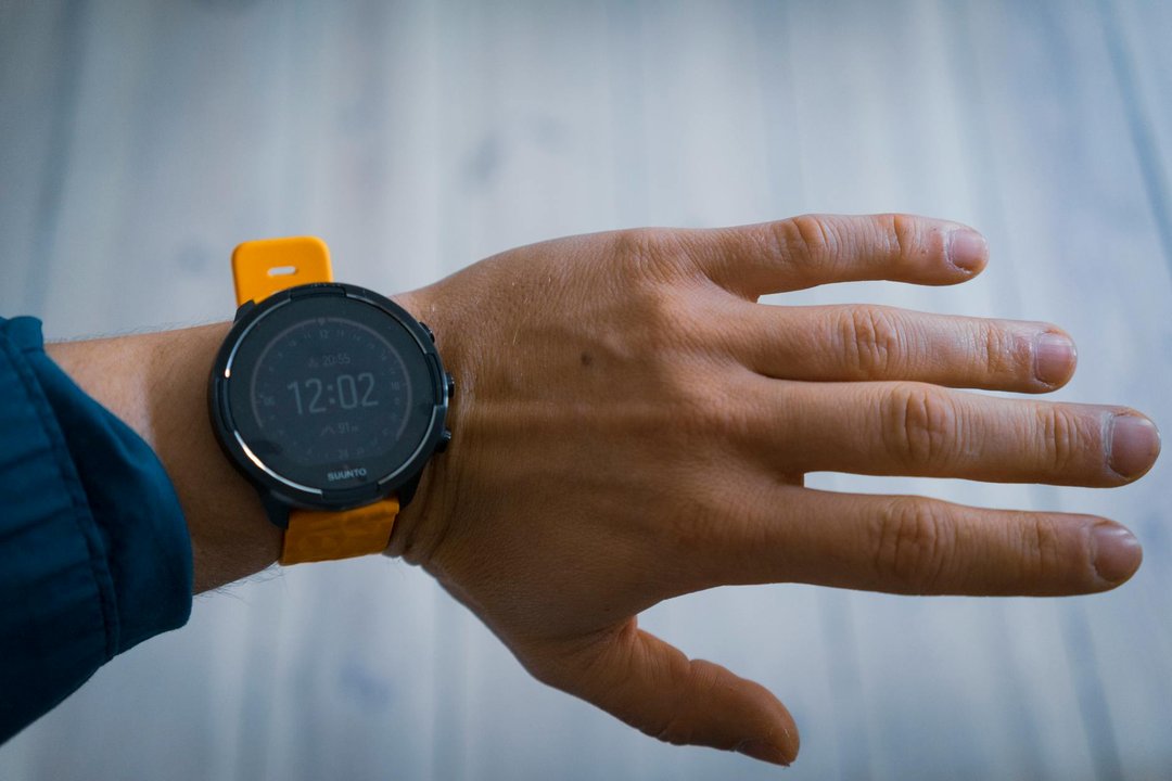 Detaliu cu un ceas smartwatch de sport purtat de un alergător, afișând date de antrenament pe un ecran luminos.
